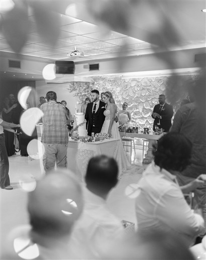 Το ζευγάρι κόβει τη γαμήλια τούρτα μπροστά σε λουλουδένιο φόντο